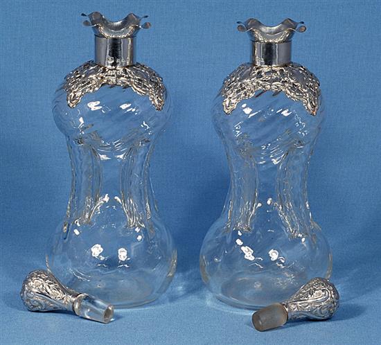 A pair of Edwardian silver mounted waisted glass decanter and stoppers,